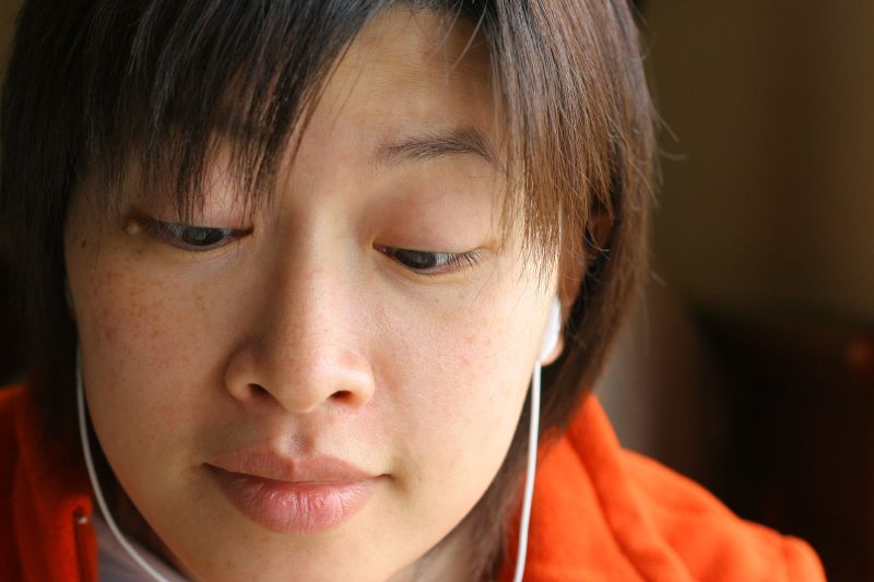 young woman looking at her cell phone while listening