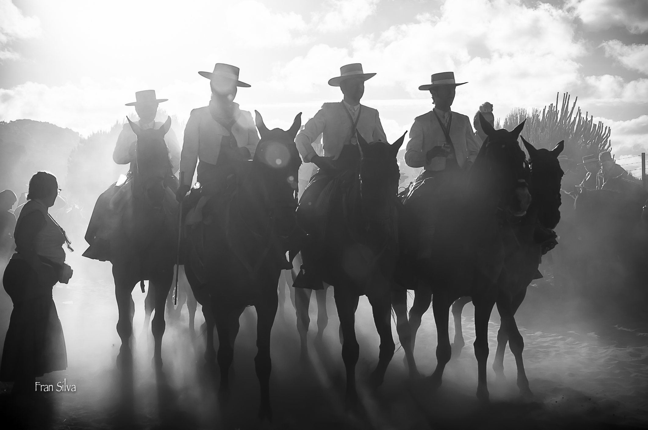 several men ride horses along in the dust