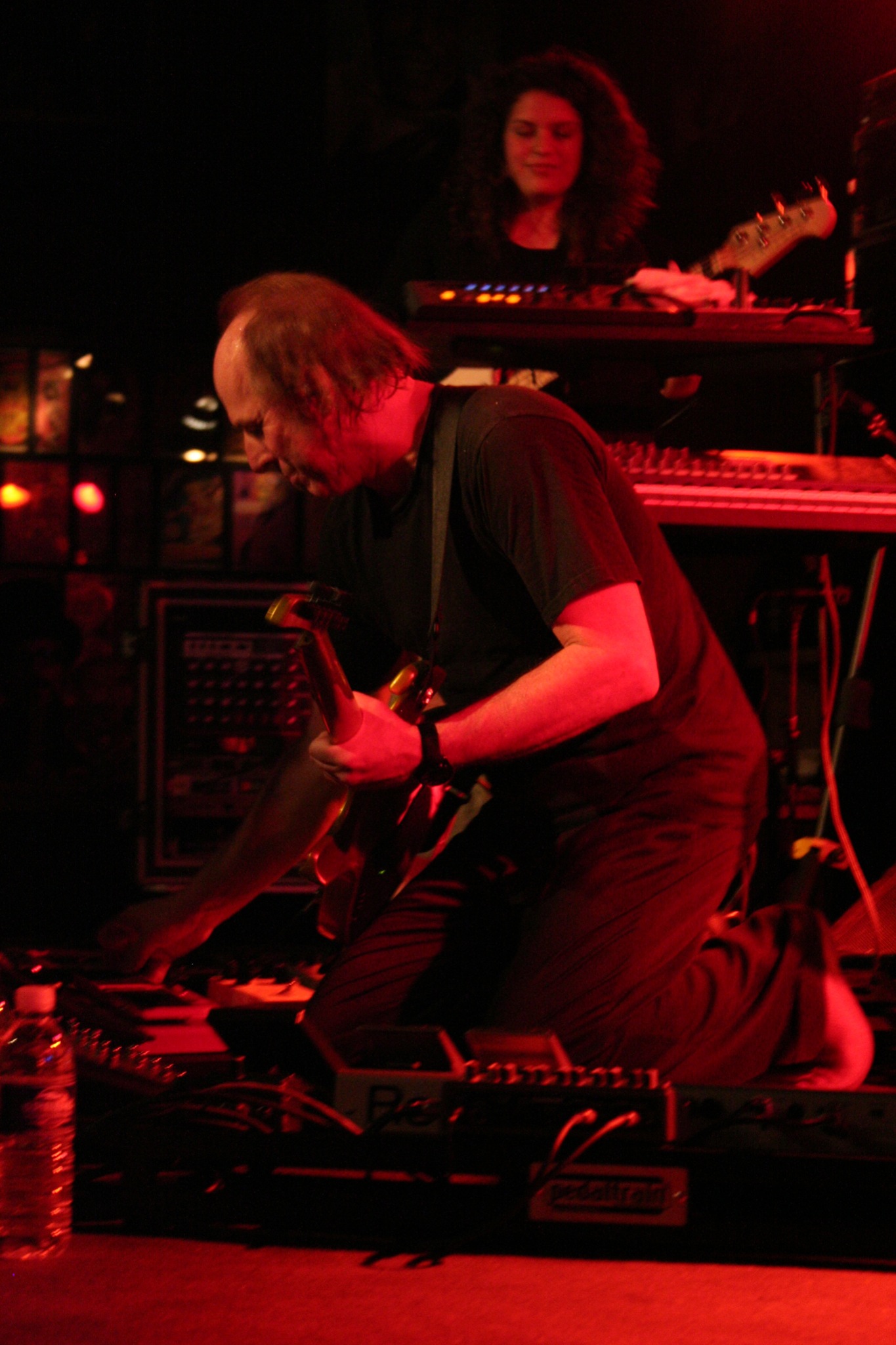 a man sitting down holding his guitar and looking down