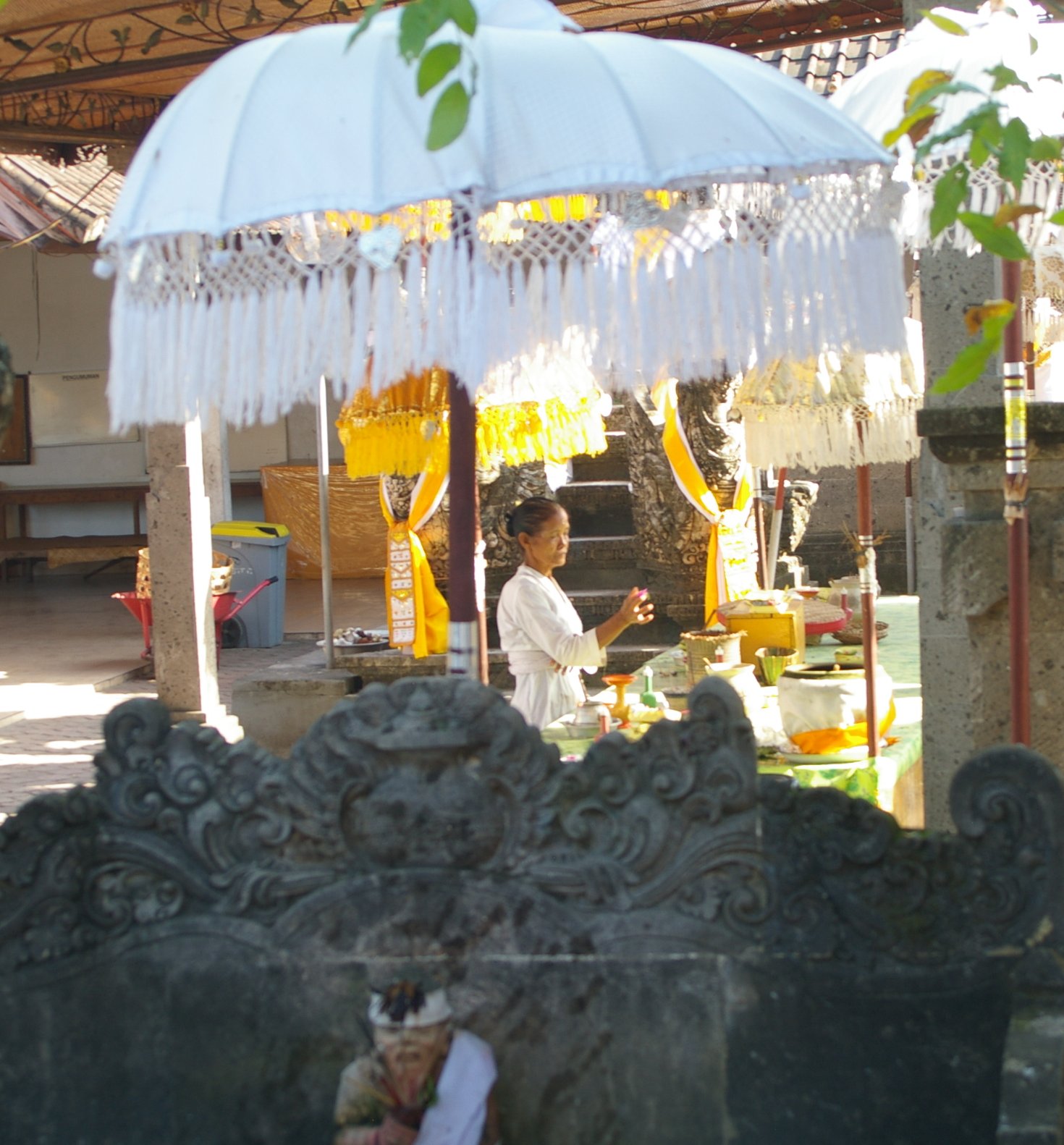 people are in a temple and a woman sits under an umbrella