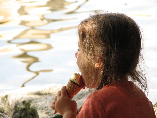 a little girl sitting on rocks eating a donut