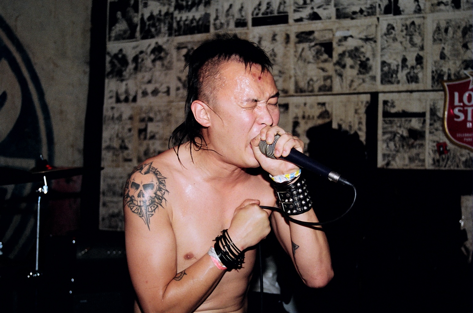 a man with tattooed arm singing into a microphone