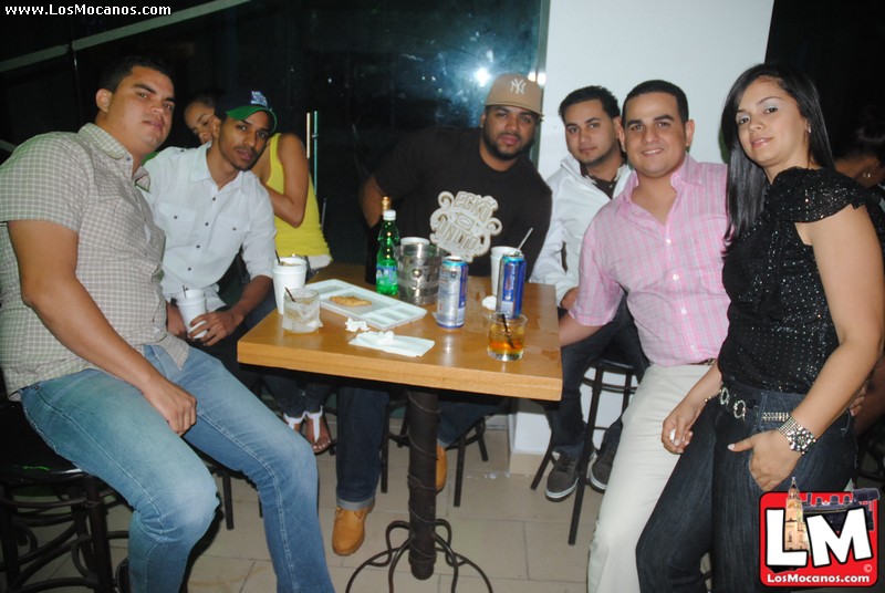 a group of men are sitting at a table drinking beers