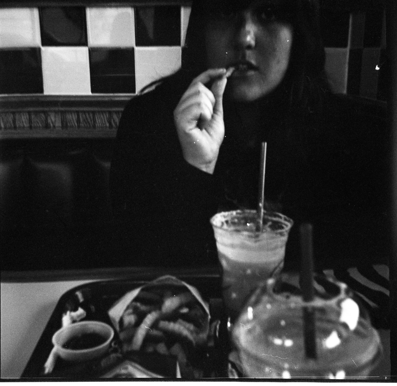 a woman eating at a diner with an odd looking drink