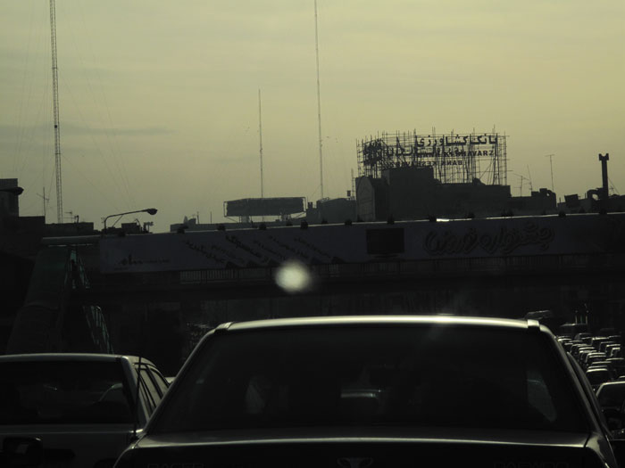 the view of the roof and part of a building in the distance from a crowded parking lot