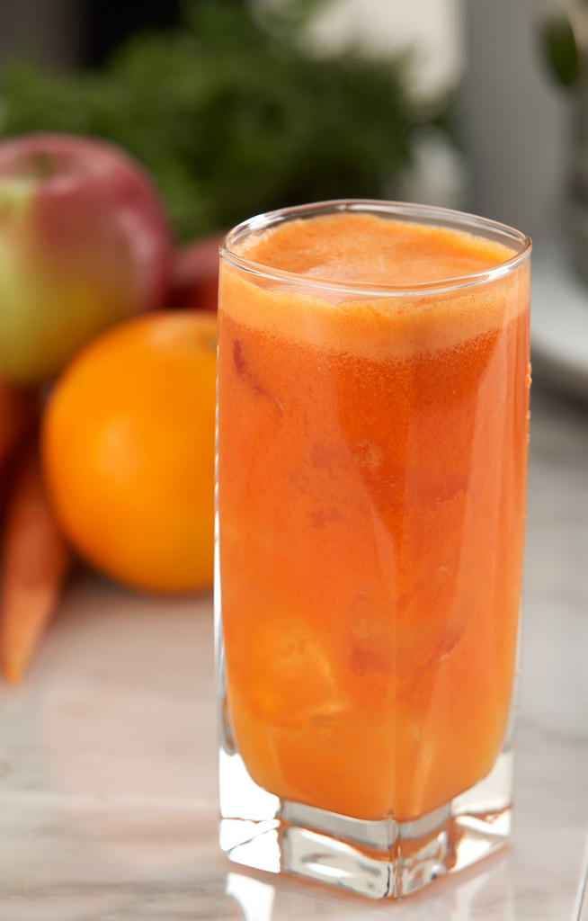 a glass filled with an orange juice surrounded by fruit