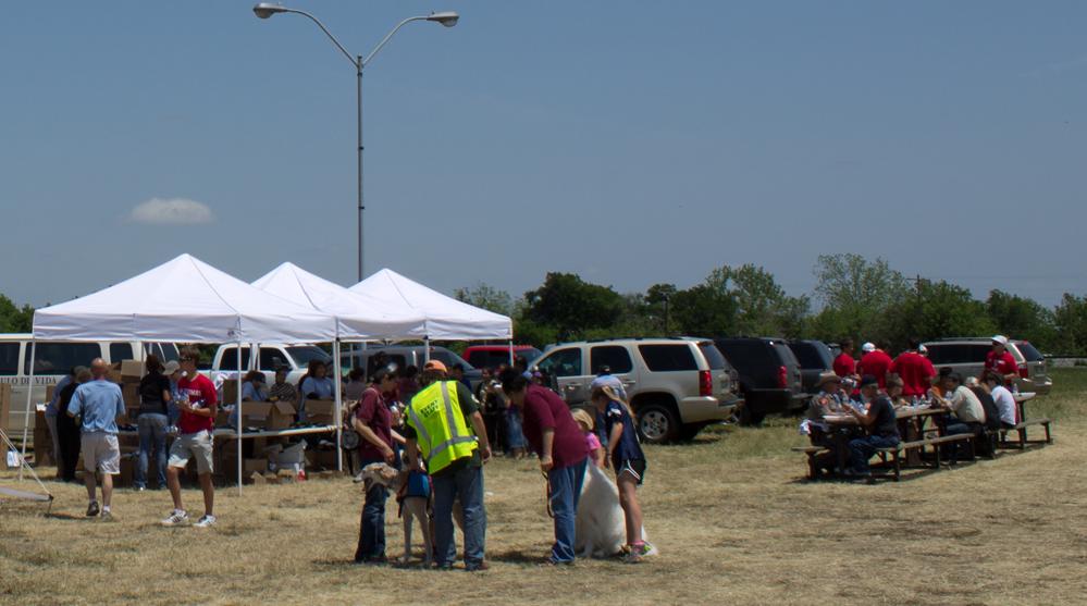 a large group of people stand around tents with food in the middle