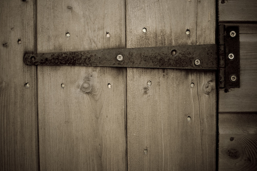 an open wooden door has metal handles
