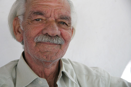 an older man wearing a tie and a beige shirt