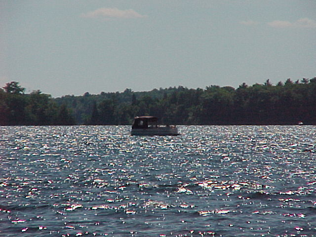 a boat floating on the water with trees in the background