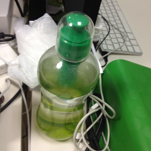 an apple green water bottle sitting on top of a desk