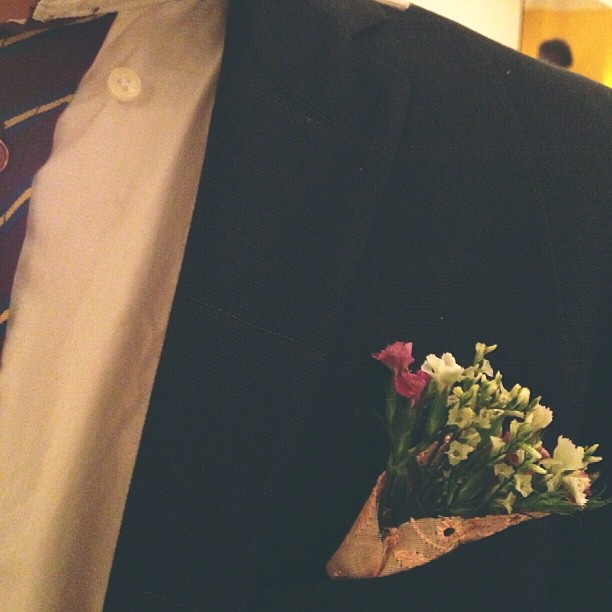 a man wearing a black jacket holding a bouquet of flowers
