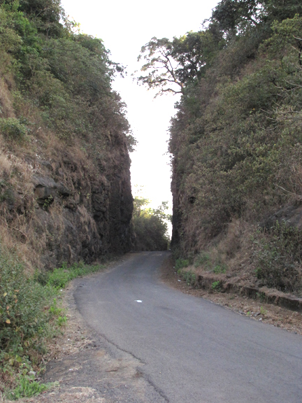 a car drives down an asphalt road between two sides of hills