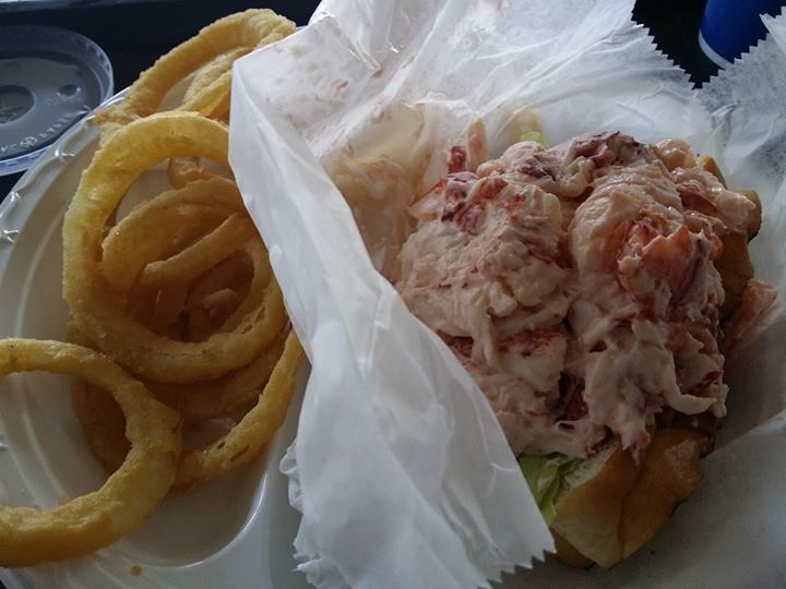 a white paper plate topped with a sandwich and onion rings