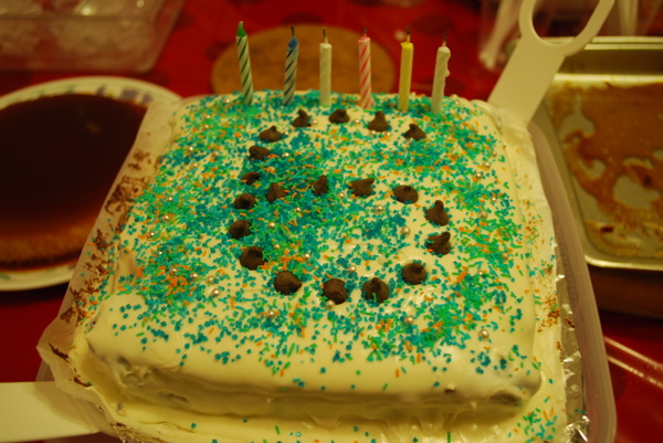 a frosted birthday cake with several lit candles