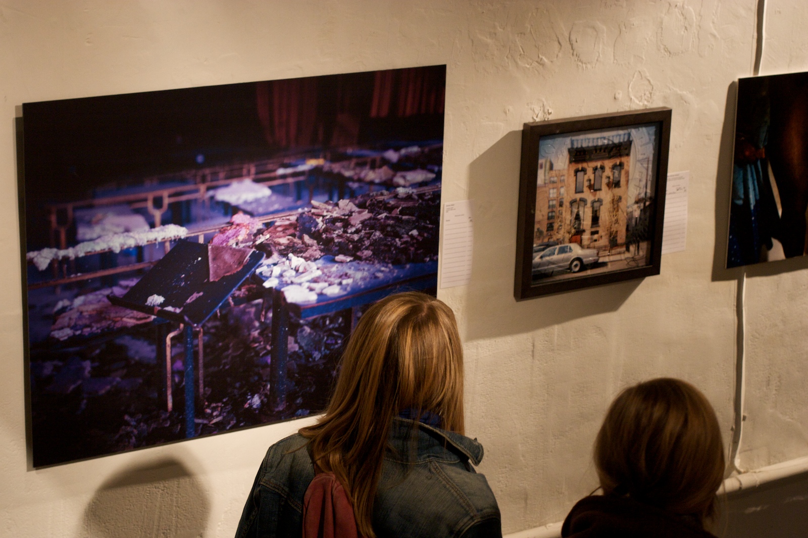 three women are watching paintings on display