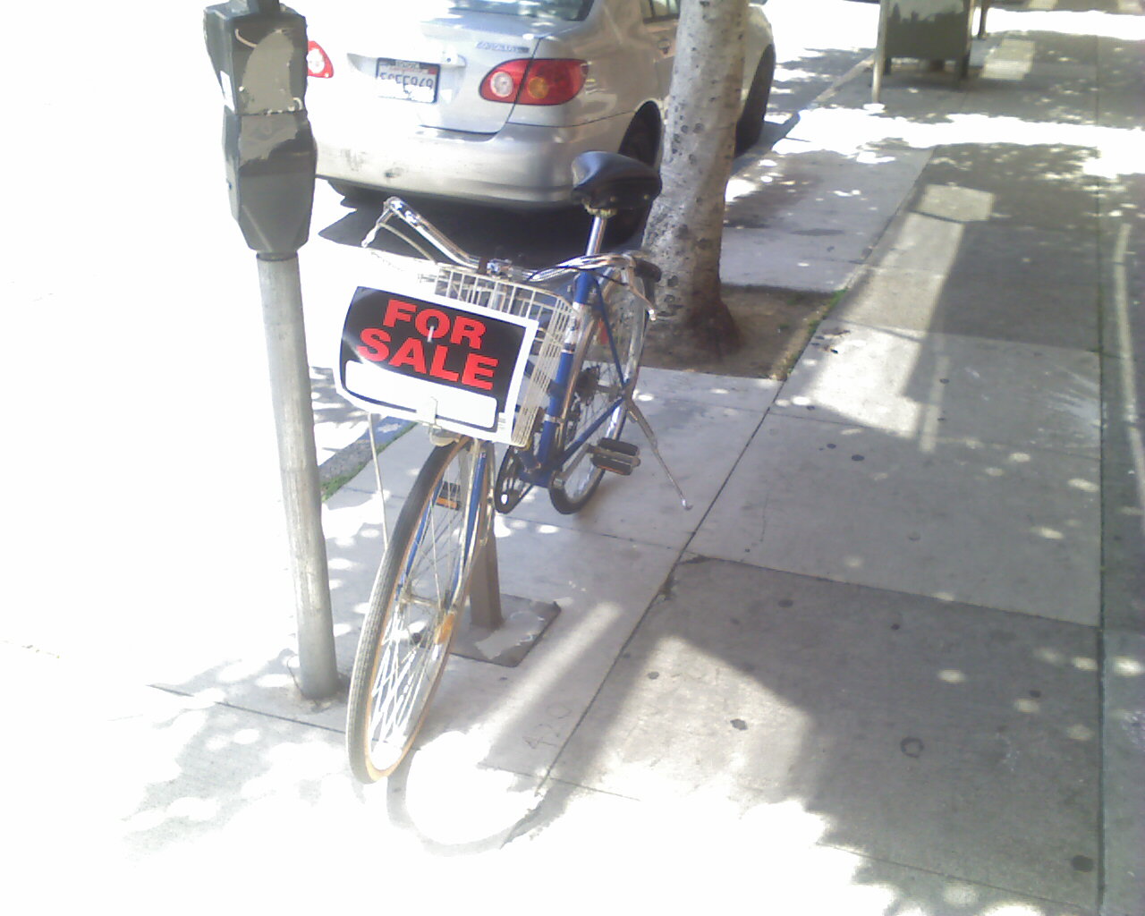 a bicycle is propped against a parking meter with a for sale sign