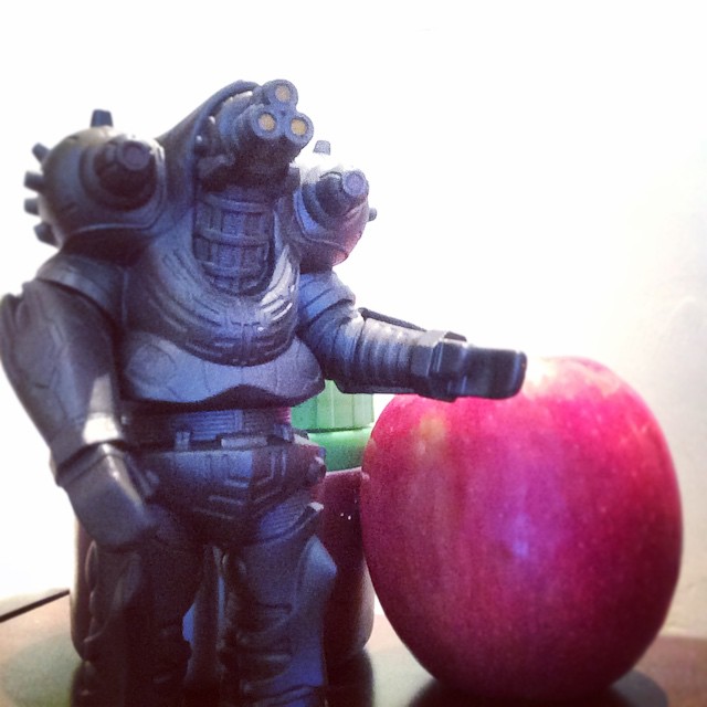 a toy is posed next to an apple