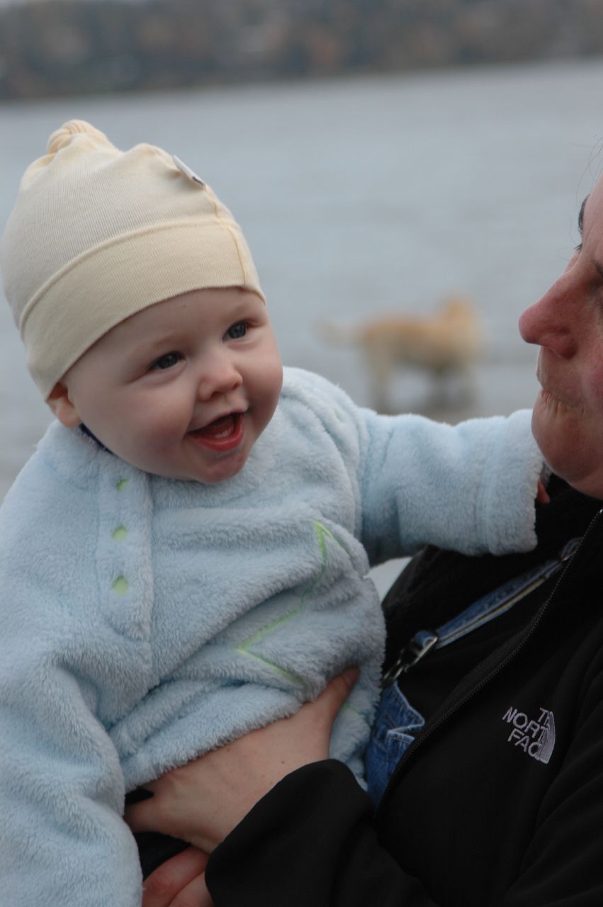 a baby holding his father's head near water