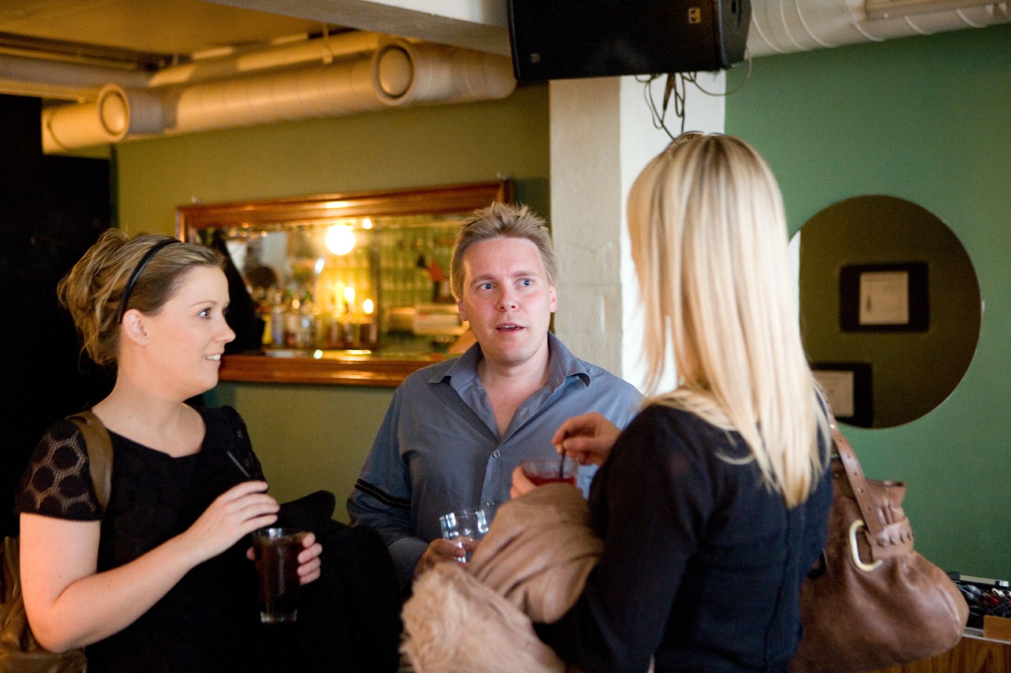 two women and a man having drinks while another woman is talking