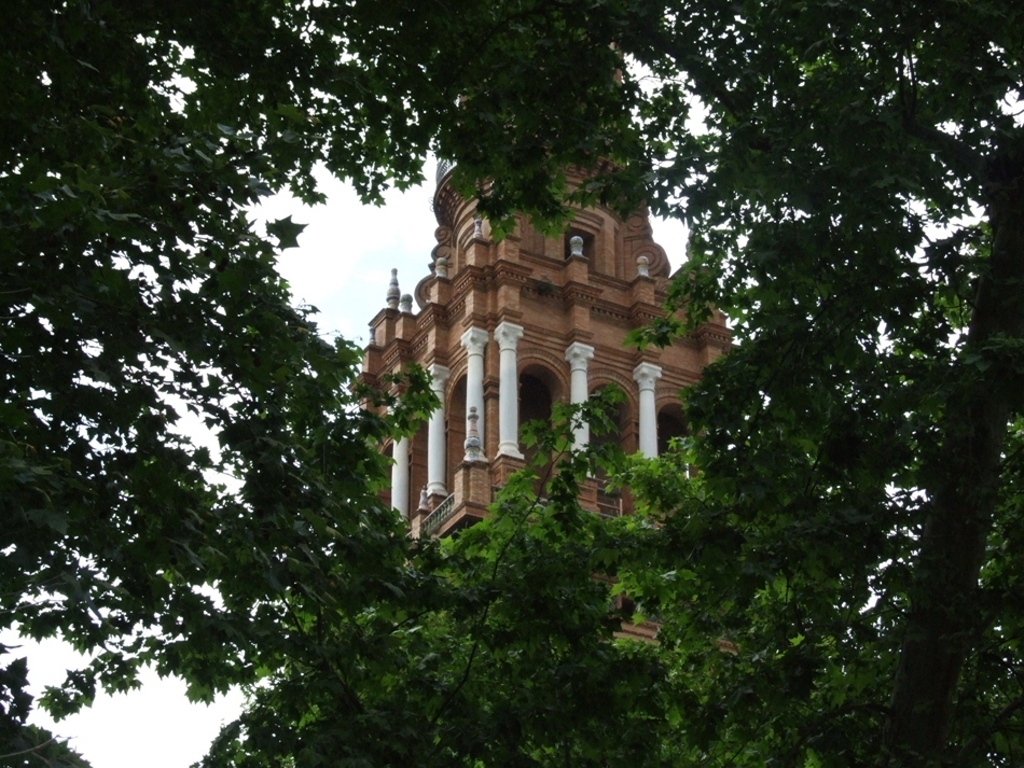 a brown building with a clock tower sitting between some trees