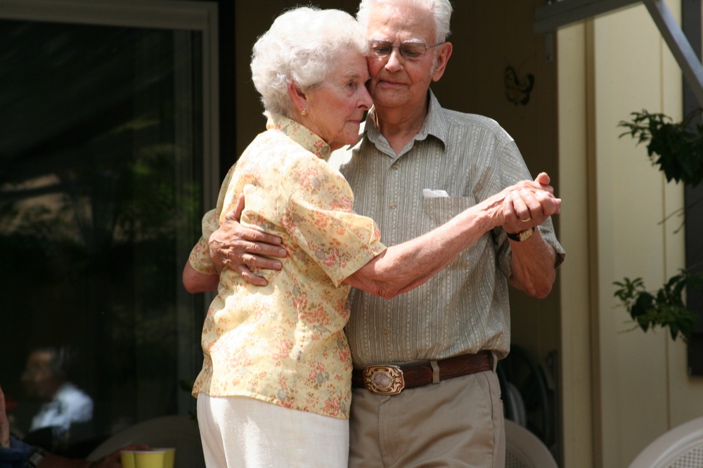 a man and woman emcing each other in front of a house