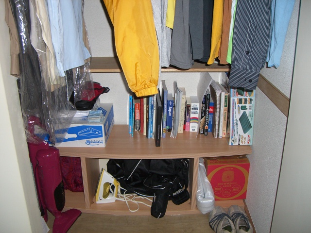 an open closet with books, papers, and coats