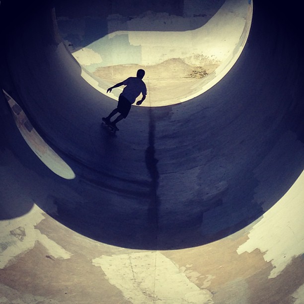 a young man riding a skateboard inside a cement pipe