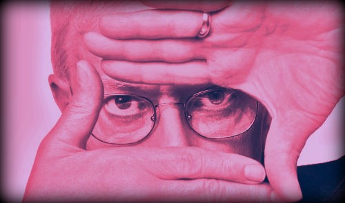 man in glasses staring through his hand on a red background