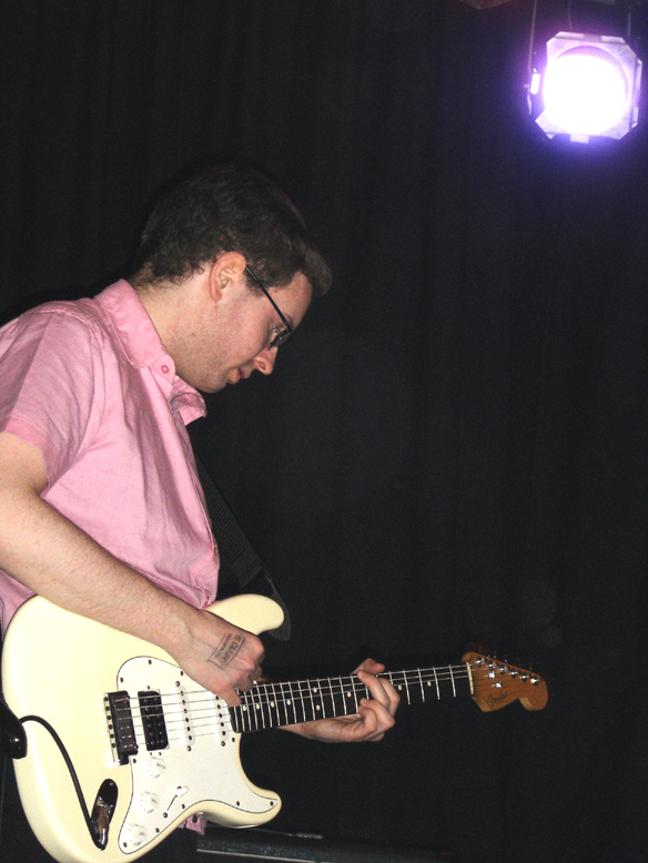 the man is playing the guitar in the dark room