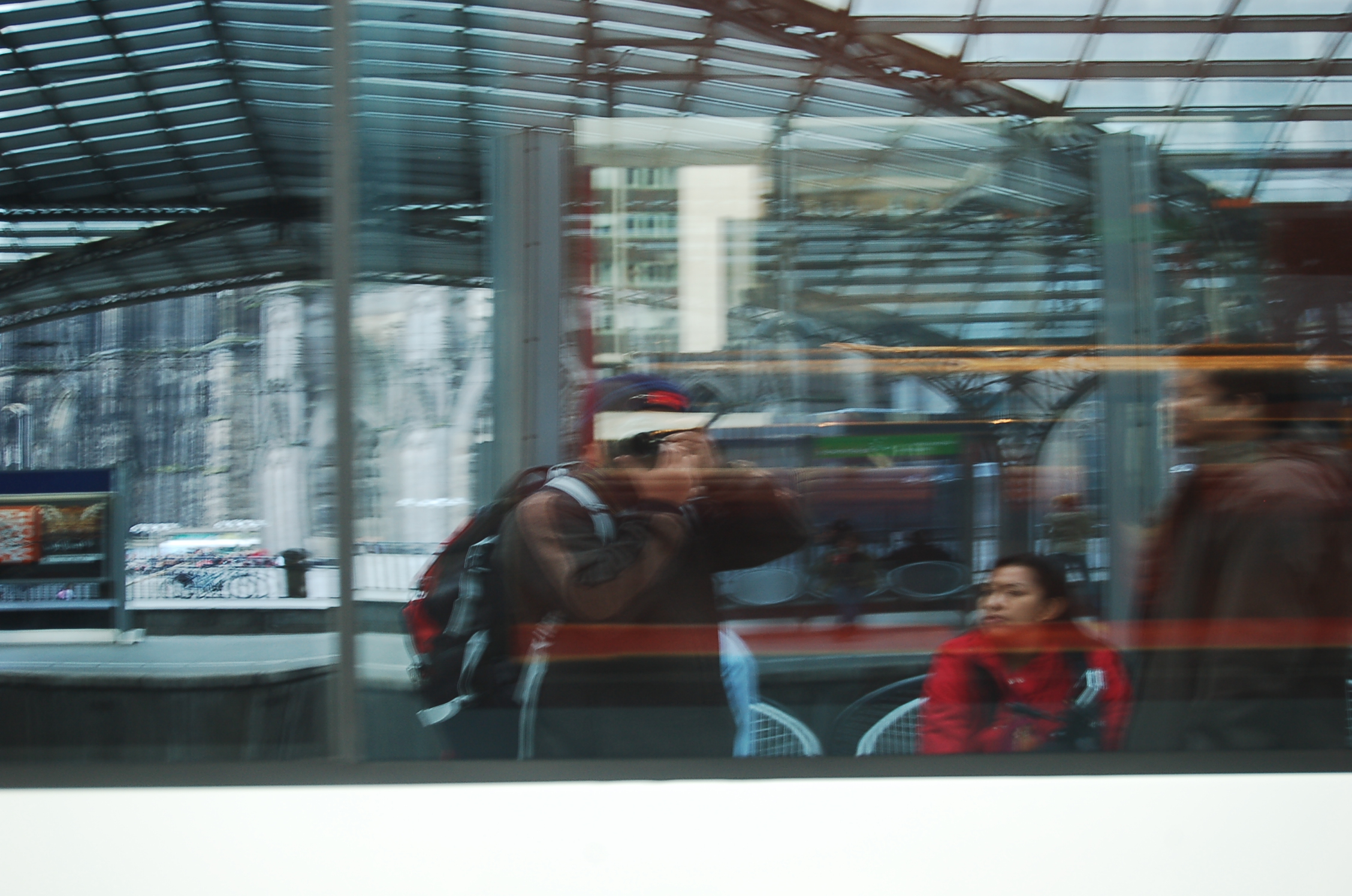 a woman with her cameraman while standing in a train station