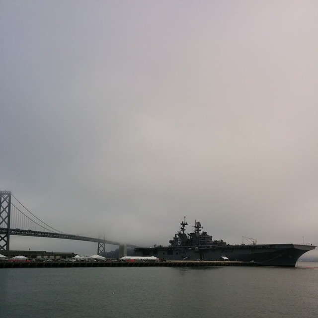 the battleship is docked by the bay bridge