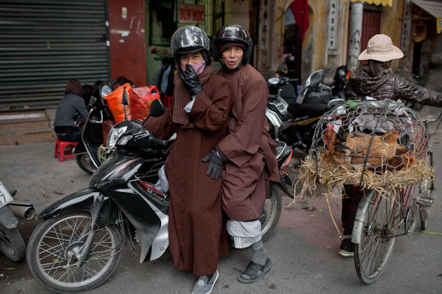 two people on a motorcycle with some stuff on the back