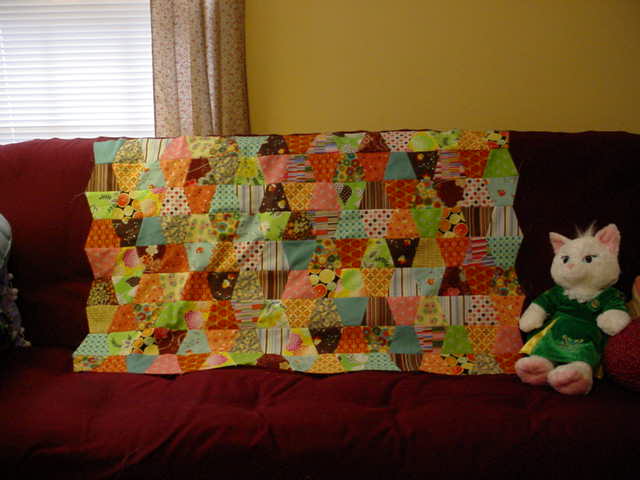 two stuffed animals sit on the couch next to a quilt