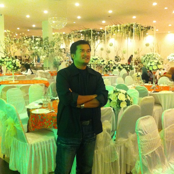 a man standing in front of rows of white and green banquet tables
