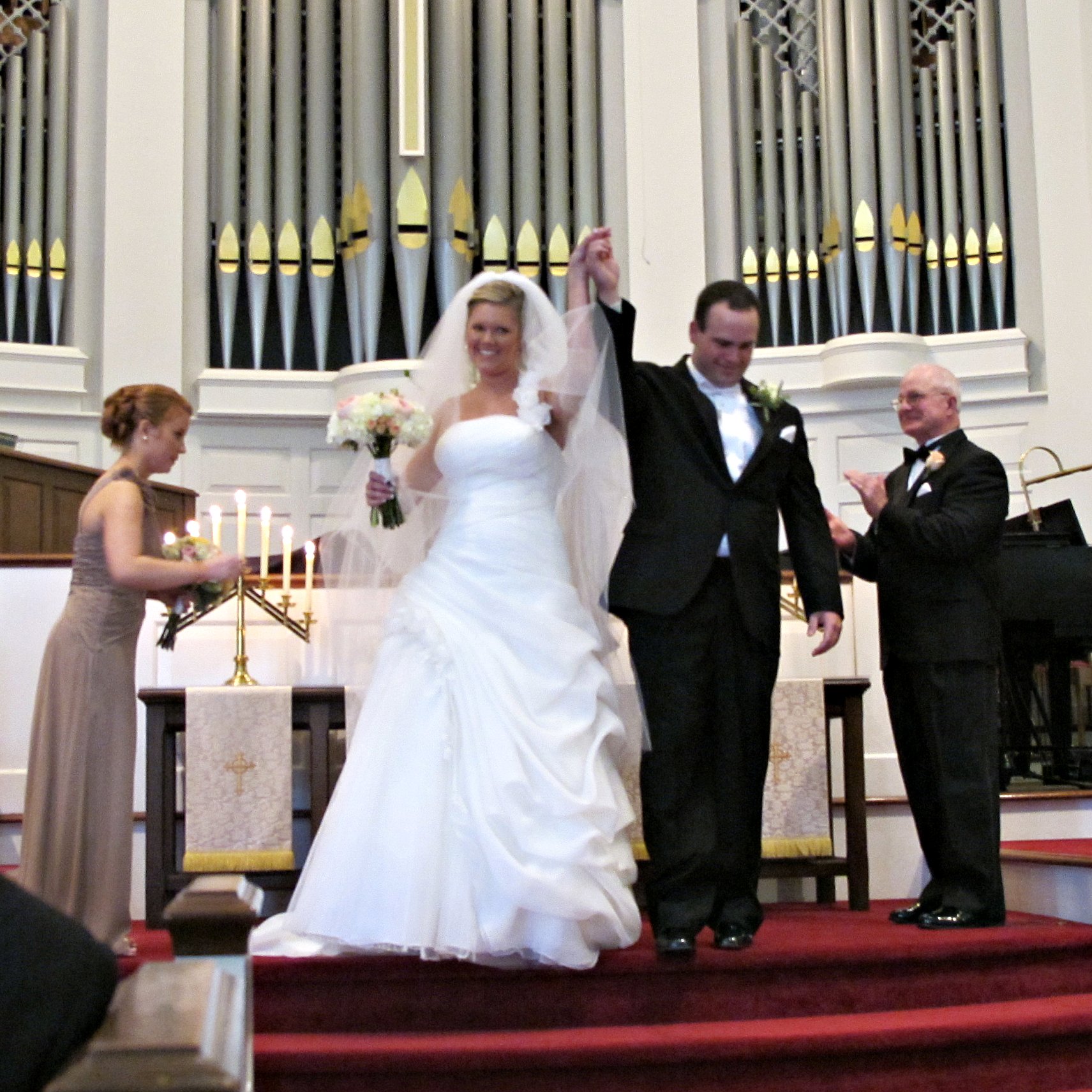 a bride and groom raising their hands as they walk down the aisle