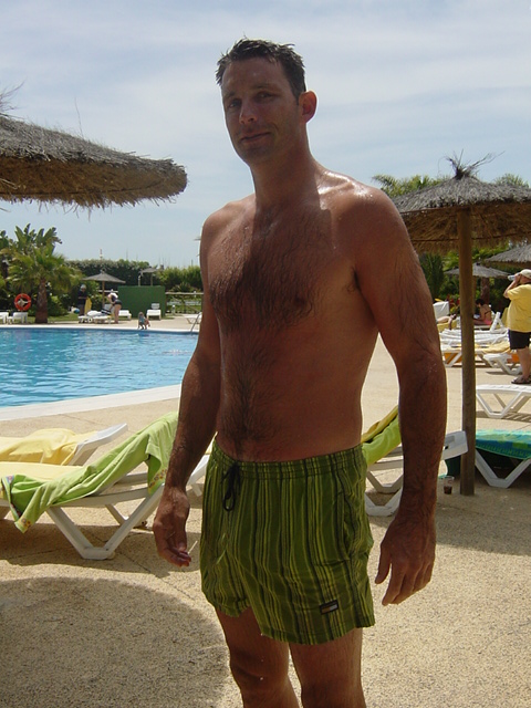 a man in green and black swim trunks and trunks on beach