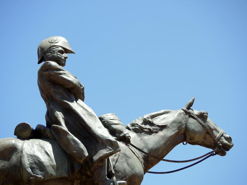 a statue of a man riding on a horse in front of blue sky