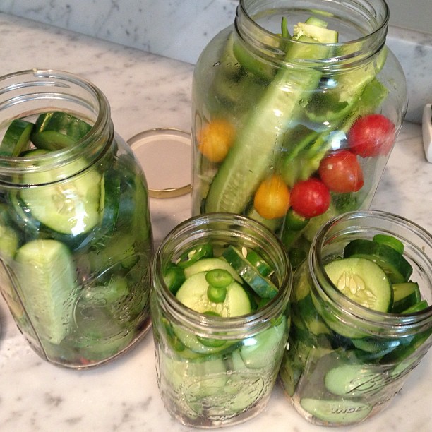 several jars with cucumbers, tomatoes and green peppers