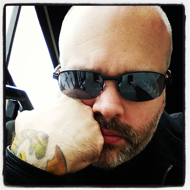 a bald headed man in black jacket and sunglasses