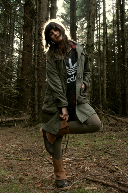 a girl standing on one leg in the middle of a forest