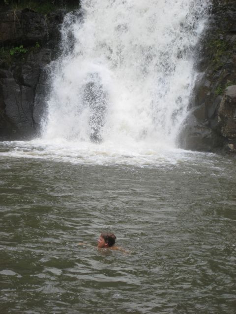 a man floating in a body of water under a waterfall
