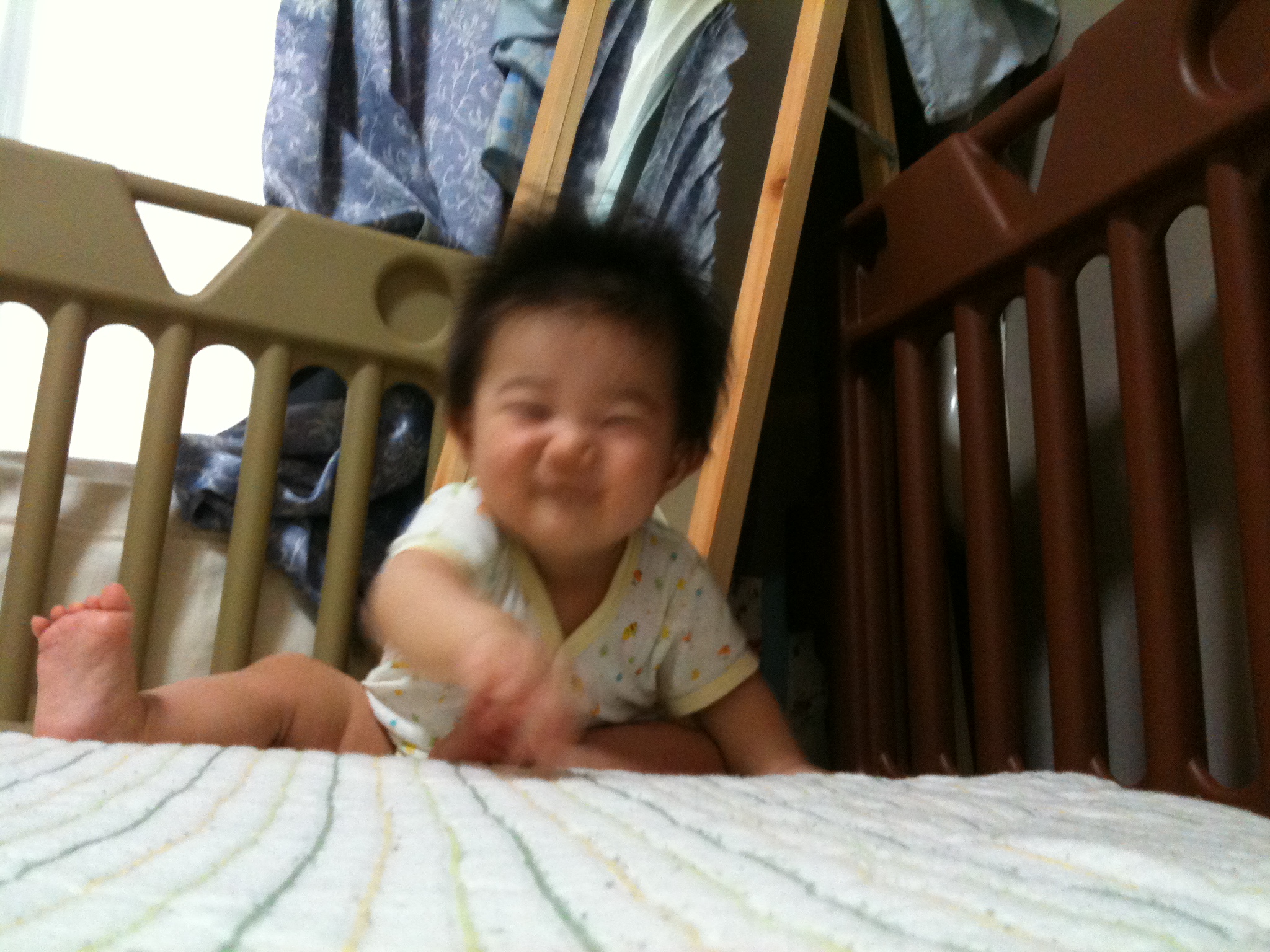baby laughing while sitting on crib next to man