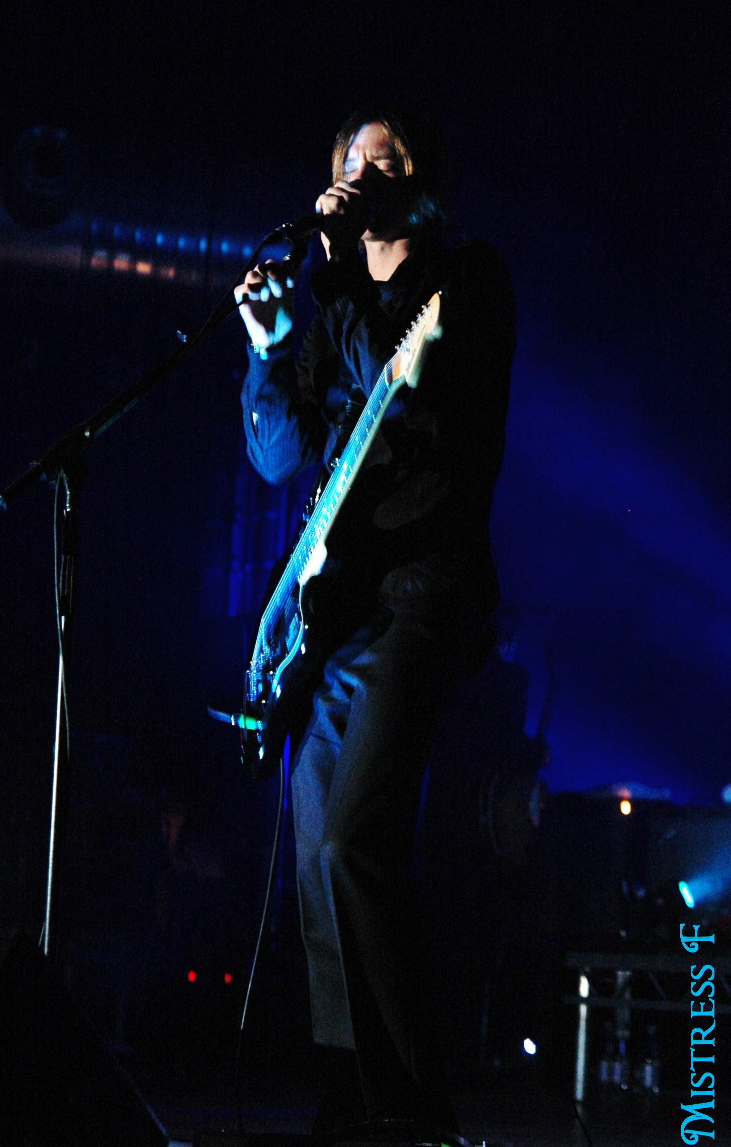 a person holding a guitar and singing on stage