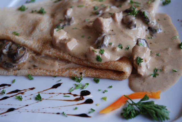 a crepe with mushrooms is on a white plate