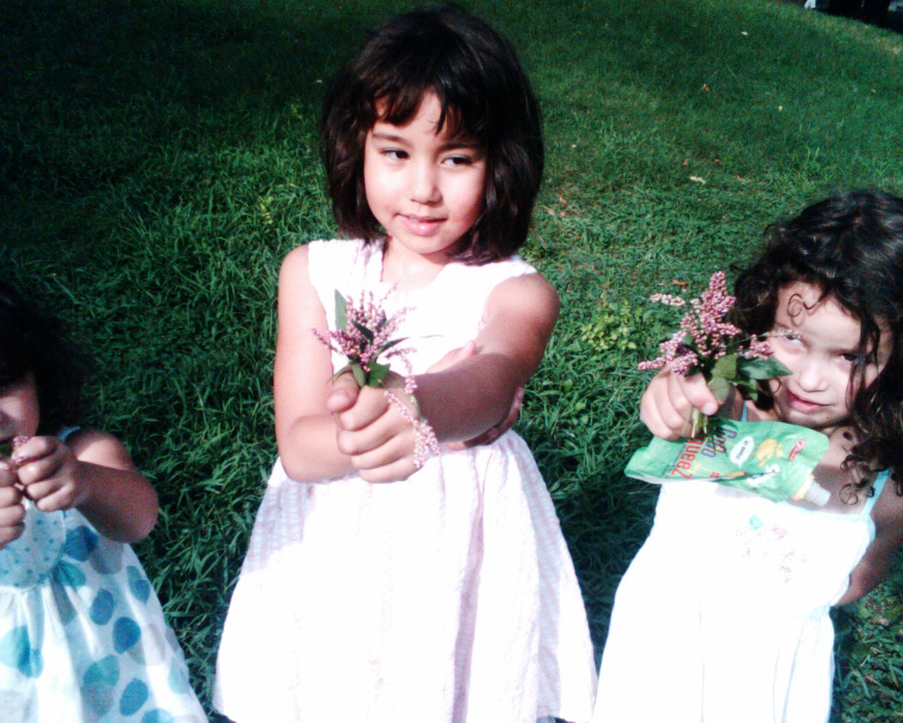 two girls are posing for the camera holding flowers