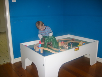 a toddler playing with a train table in the living room