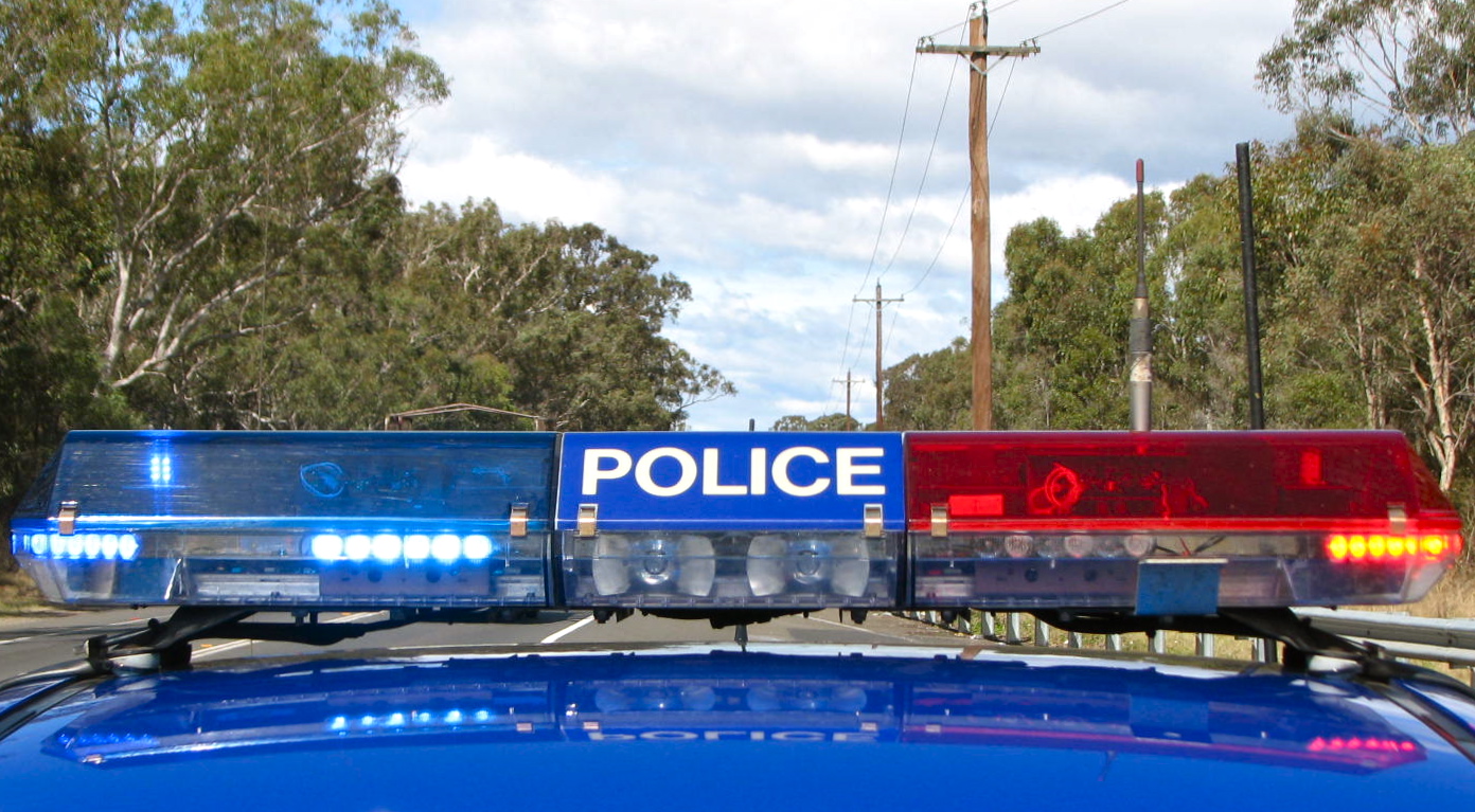 an orange, white and blue police car and its name on the light on it