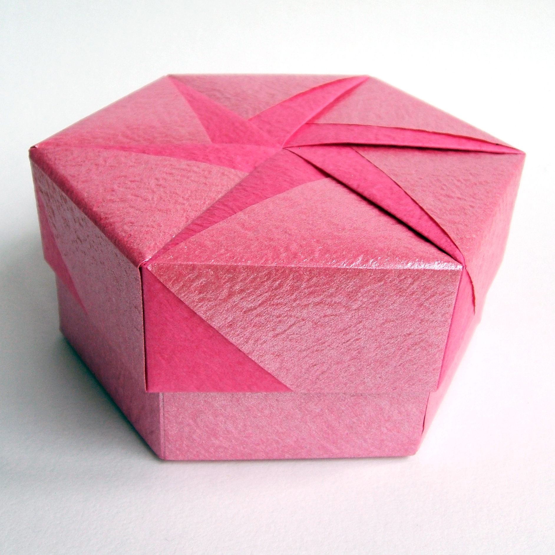 the pink paper is folded up in an intricate square