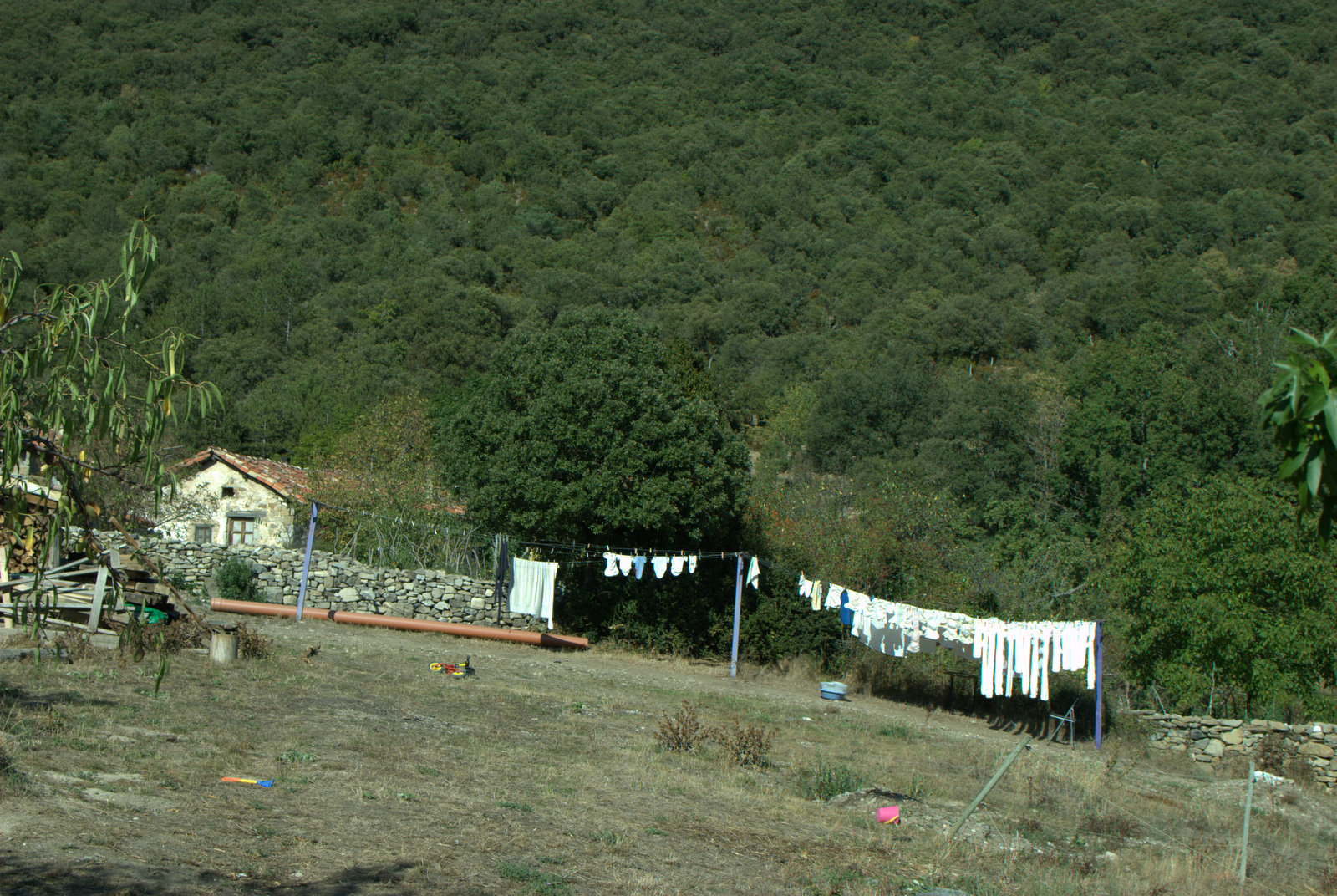a house sits at the bottom of a hill in front of clothes hanging from a line